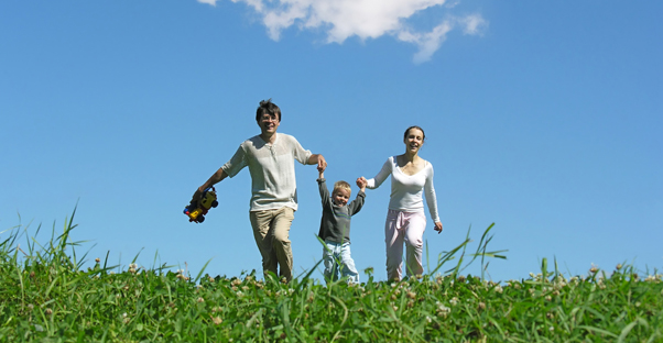 Couple carrying their child through the grass