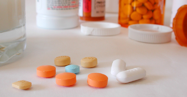 Loose pills sit in the foreground of orange pill bottles.