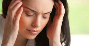 A woman massages her temples while experiencing a migraine headache.
