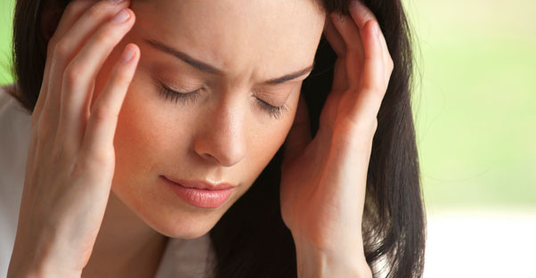 A woman massages her temples while experiencing a migraine headache.