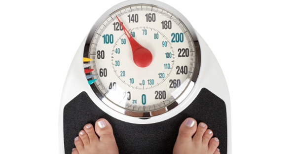 The feet of a person are visible on a scale as the needle reads 120 pounds.