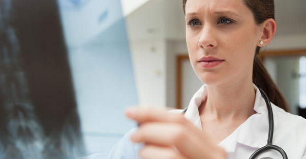a doctor examines an x-ray looking for bone cancer