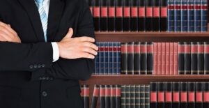 Man in a suit stands in front of a bookshelf