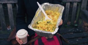 Woman holding coffee and a takeout order of fried rice