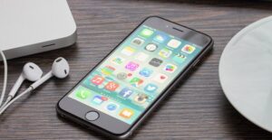 Expensive cell phone laying on a table next to earbud headphones
