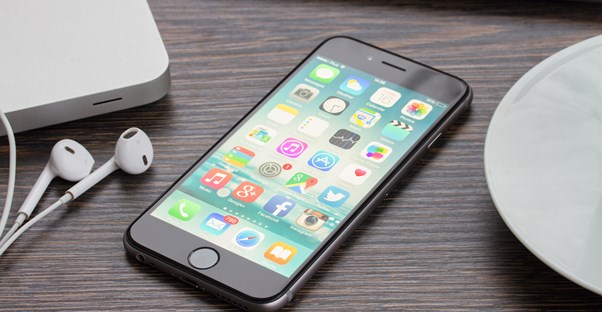 Expensive cell phone laying on a table next to earbud headphones