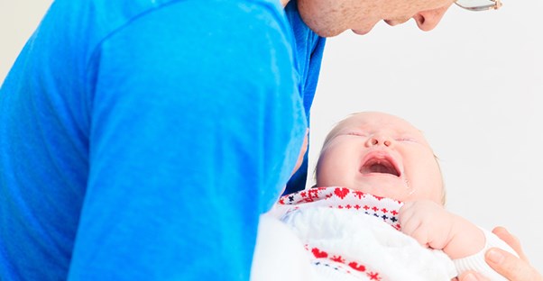 An adult human comforts a crying baby human