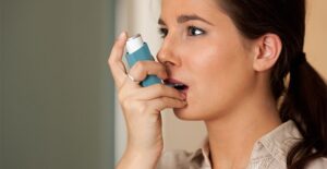 A woman uses her inhaler