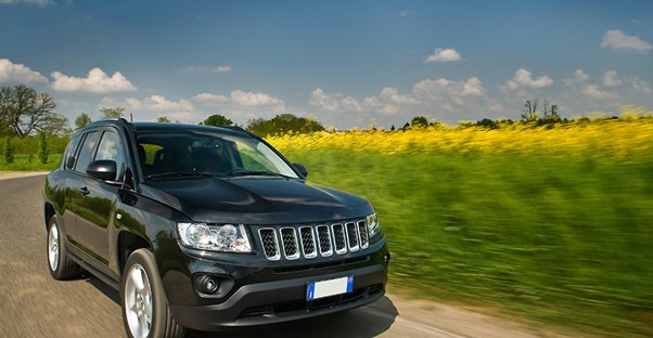 SUV driving on a road through a field