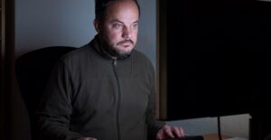 Man sitting in dark looking at computer screen