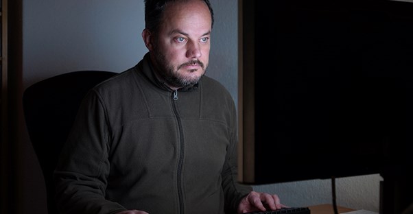 Man sitting in dark looking at computer screen