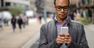 Man holding a noncontract cell phone on a busy street