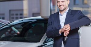 smiling guy standing next to a car