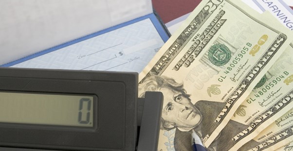 calculator and checkbook with cash for saving for retirement