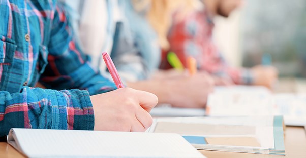 students writing on paper sitting at desk at community college