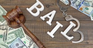 bail letters and hand cuffs next to gavel and money