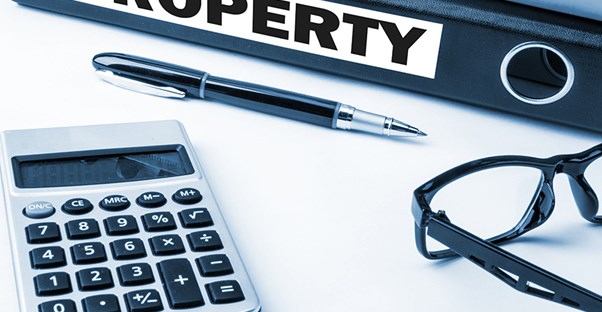rental property binder with pen glasses and calculator on desk