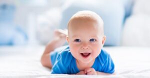 smiling baby laying on a bed