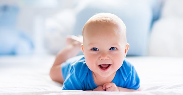smiling baby laying on a bed
