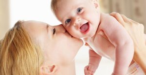 mom kissing smiling baby on the cheek