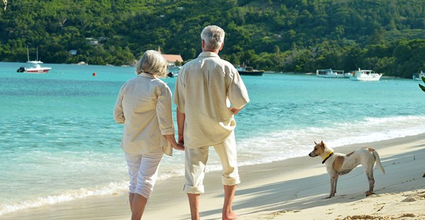 A retired couple walk the beautiful beaches of Tulum, Mexico, with their dog.