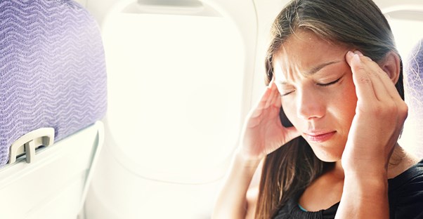 A woman massages her head while suffering from jet lag on her flight.