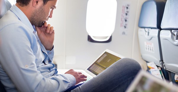 A typical business traveler checks his laptop for updates while on a plane.