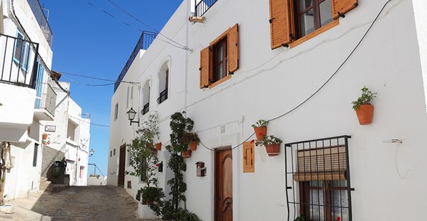 Stark white homes crowd a narrow Greek cobbled street.