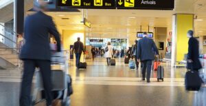 Passengers walk through an airport concourse toward the departure gate.