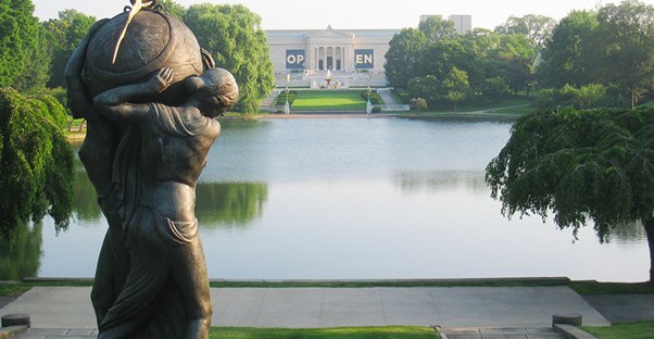 A sculpture with its back to the camera overlooks the reflecting pool in front of the Cleveland Museum of Art.