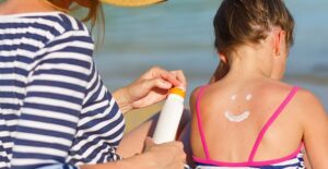 A woman applies sunscreen to a child