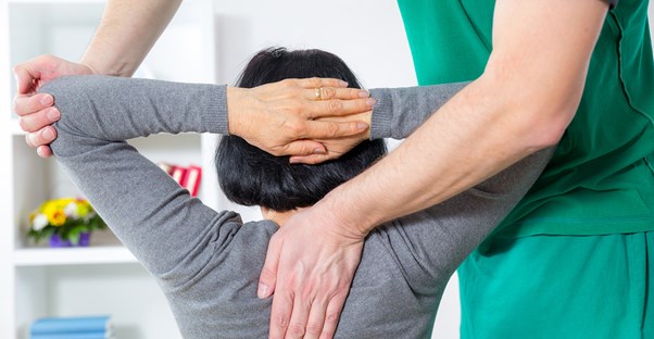 a physical therapist helps a woman with her spine pain