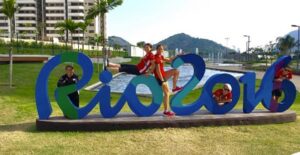 Olympic athletes pose on a Rio sign in the Olympic Village.