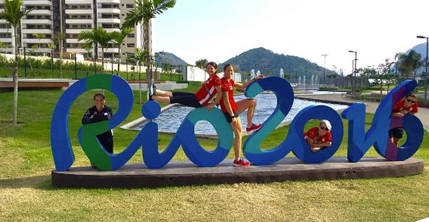 Olympic athletes pose on a Rio sign in the Olympic Village.