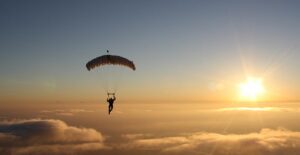 A parachuter floats through the air toward the sunset.
