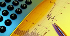 Calculator and pen resting on top of a line graph showing the latest changes in commodity prices
