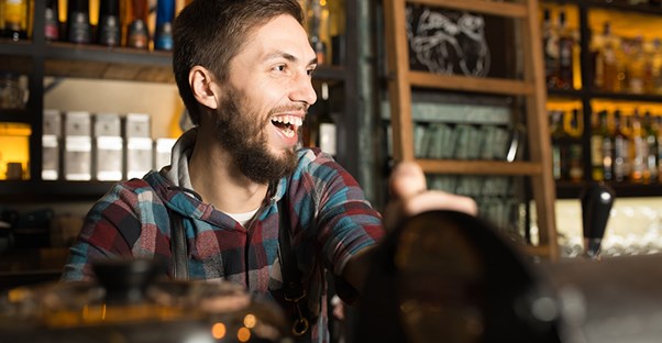 a young entrepreneur running his own successful bar smiling and interacting with guests