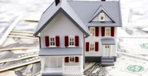 a play house sitting on top of a bunch of dollar bills to show that escrow is involved with protecting money