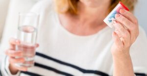 woman holding pills and a glass of water to treat salmonellosis