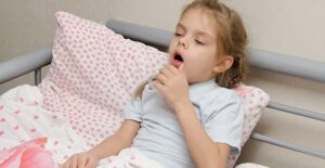 child coughing in her bed