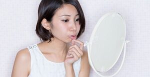 girl looking at her chapped lips that are caused by dry mouth