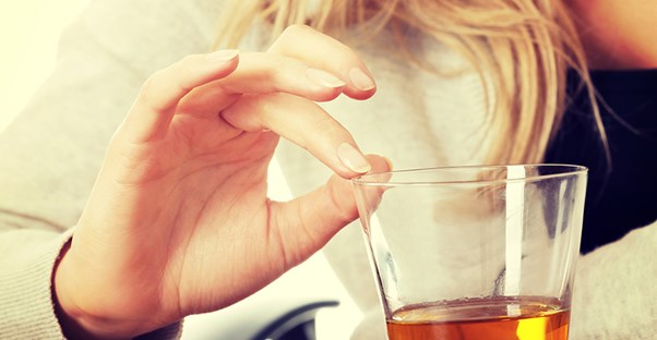 woman resisting a drink of alcohol because she is having delirium tremens symptoms