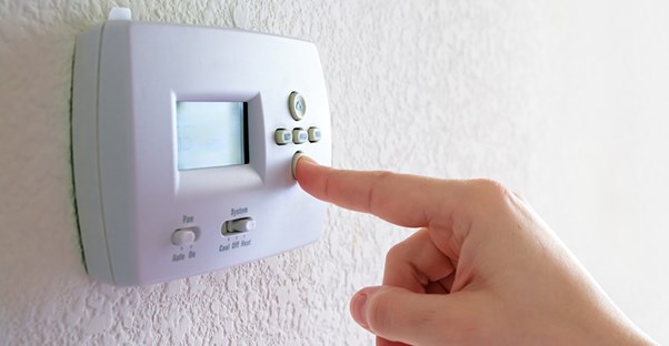 A homeowner adjusts the thermostat