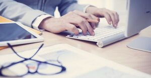 Man searching on laptop for information about business administration degrees