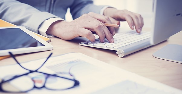 Man searching on laptop for information about business administration degrees