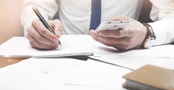 a man writing down contact info from his phone for a job he got with a business administration degree