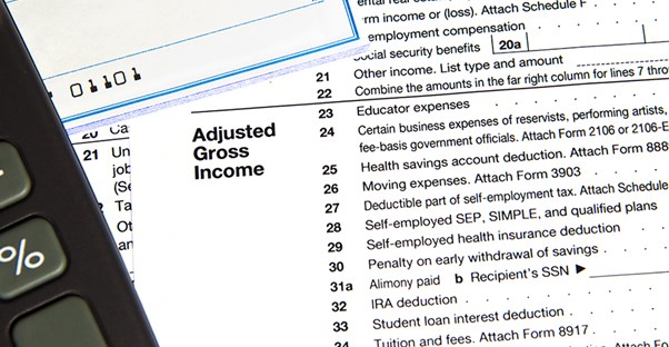 Adjusted gross income filing sheet under check and a calculator
