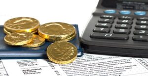 coins, check book, and calculator sitting on top of an adjusted gross income calculation form
