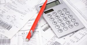 calculator and pen on top of last year's receipts to calculate previous year AGI for the IRS
