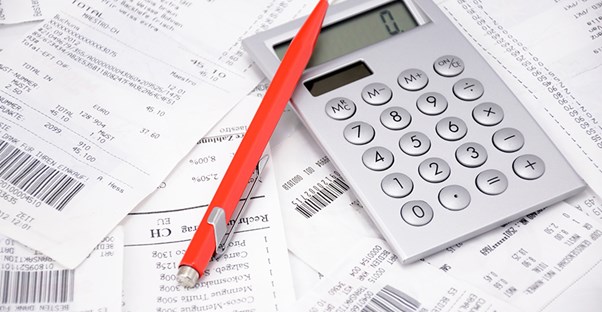 calculator and pen on top of last year's receipts to calculate previous year AGI for the IRS